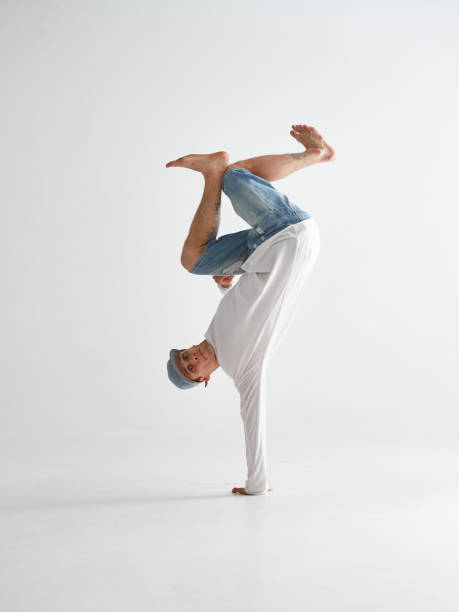 istock Cool breakdancer stands on one hand upside down dancing hip-hop isolated on white background. Break dance school poster 1265611198