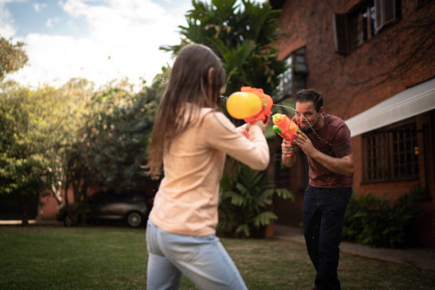 istock Father and daughter playing with squirt gun in the backyard 1265611769