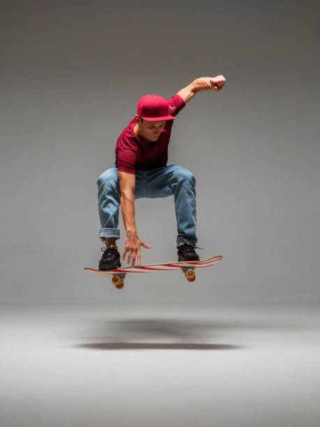 istock Cool young guy skateboarder levitates on skateboard in studio on grey background. Photography about skateboarding tricks 1265611937