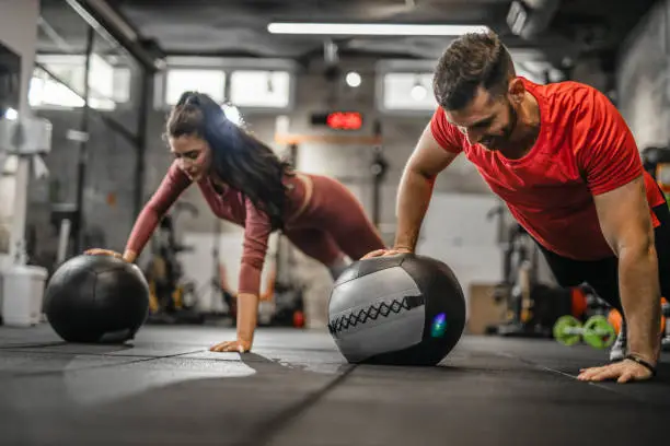 Sportswoman and sportsman balancing on a medicine ball during a workout