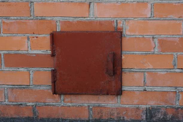 red lid on a small square entrance on a brown brick wall
