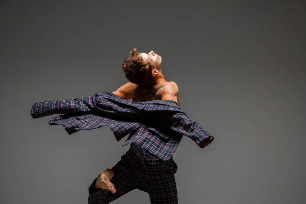 istock Stylish young guy dancer in suit dancing modern expressive dance in studio. Dance school poster. Dance lessons 1265614357