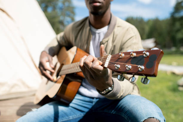 istock Black man playing guitar at campsite 1265615291