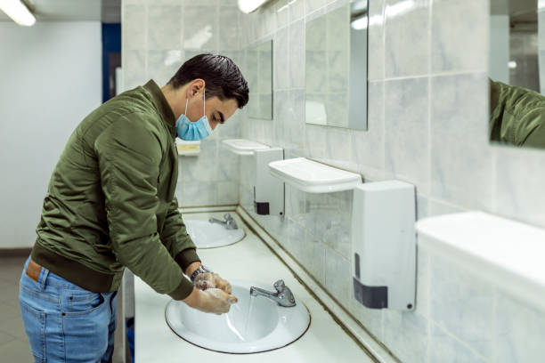 istock Man washing his hands to avoid diseases like coronavirus Man with a face mask washes his hands in a public bathroom 1265617101