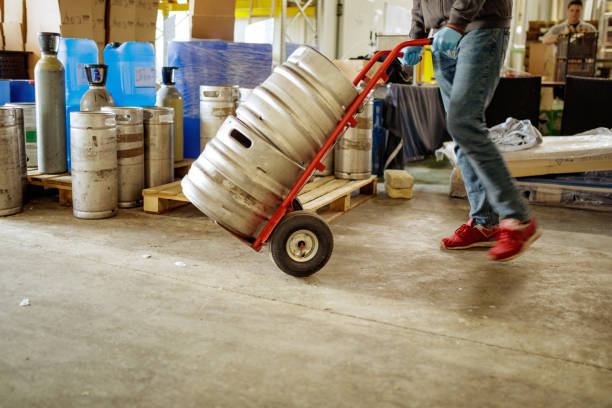 sección baja del trabajador del almacén empujando barriles en el carro - industry warehouse floor beer fotografías e imágenes de stock