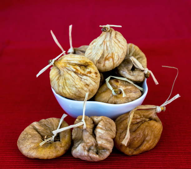 istock Healthy food: dried figs in white bowl on red cloth napkin on the table, closeup , selective focus 1265618695
