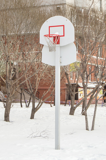 Basketball basket against the background of trees and houses, in the open, against the winter landscape.