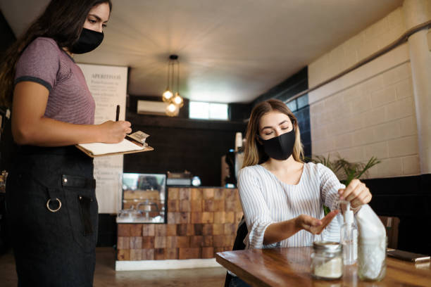 istock Female client in coffee shop putting antibacterial gel in hands 1265620704