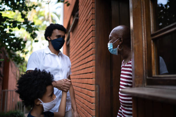 istock Son visiting mother at home during pandemic using surgical mask 1265622866