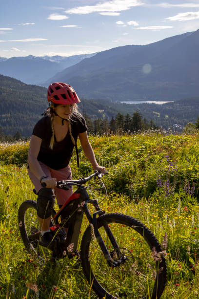 istock Young woman mountain biker rides up mountain meadow 1265625518