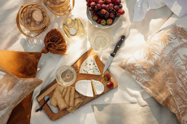 Wine and cheese picnic outdoors in summer \nPhoto of picnic blanket and food and drink in summer sunshine sunlight