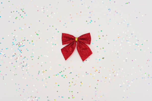 composizione minimale natalizia. fiocco rosso isolato su sfondo bianco con glitter. concetto di capodanno. copiare lo spazio. - bow satin red large foto e immagini stock