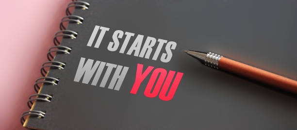It Starts With You words printed in notebook and pen. Motivation concept