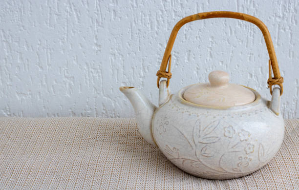 istock An old light clay teapot with cracks and scratches on a white background. 1265638837