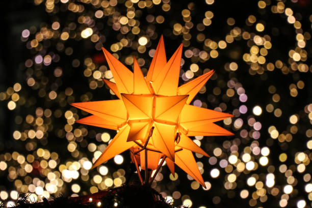 Cologne, Germany - December 2, 2018: Close up view of Moravian christmas star with Bokeh lights in background. Photo taken in Cologne christmas market. The stars take their English name from the Moravian Church, originating in Moravia. In Germany, they are known as Herrnhut stars, named after the Moravian Mother Community in Saxony, Germany, where they were first commercially produced.