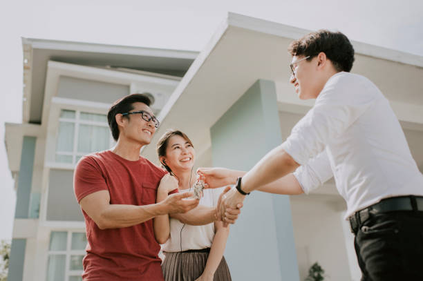 una famiglia cinese asiatica che si trasferisce in una nuova casa e ha ricevuto la chiave della casa da agente immobiliare - tasto pgsù foto e immagini stock