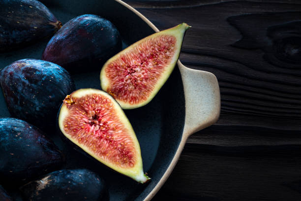 Figs ripe fruits cut on dark wood low key moody light