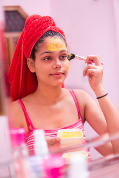 istock Beautiful girl applying yellow turmeric face pack on face. 1265651494