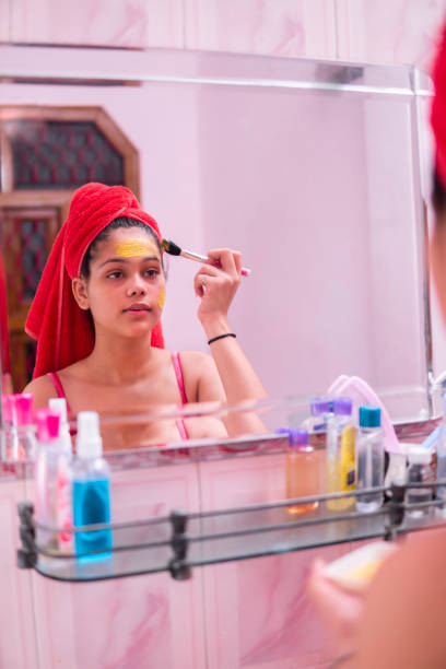 istock Beautiful girl applying yellow turmeric face pack on face. 1265651523