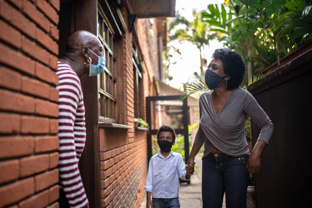 istock Daughter visiting mother at home during pandemic using surgical mask 1265652095