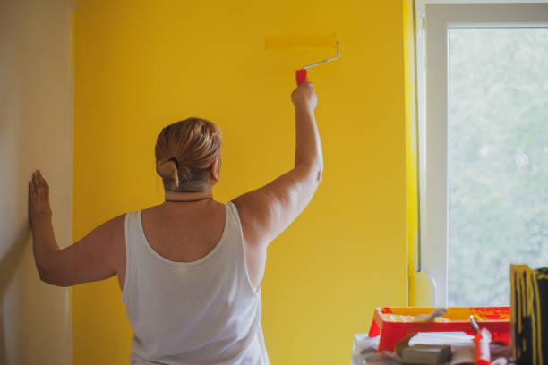 istock Painting a wall in yellow with paint roller 1265652340