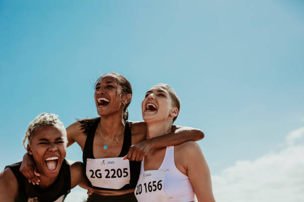 Group of female runners enjoying victory Young team of female athletes standing together and screaming in excitement. Diverse group of runners enjoying victory. track and field athlete stock pictures, royalty-free photos & images