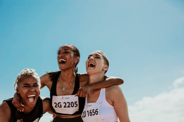 Group of female runners enjoying victory Young team of female athletes standing together and screaming in excitement. Diverse group of runners enjoying victory. sports team event stock pictures, royalty-free photos & images