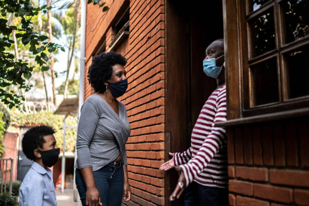 istock Daughter visiting mother at home during pandemic using surgical mask 1265653798