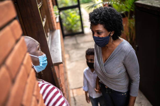 istock Daughter visiting mother at home during pandemic using surgical mask 1265653962