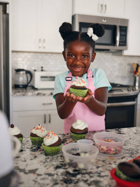 istock Little Girl Baking Cupcakes in a Home Kitchen 1265655295