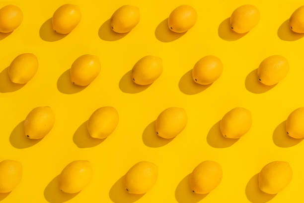 Studio shot of lemons with shadows on a yellow background. A modern look with many conceptual interpretations.