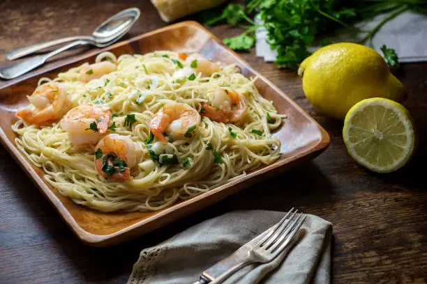 Shrimp scampi with angel hair pasta surrounded by cooking ingredients