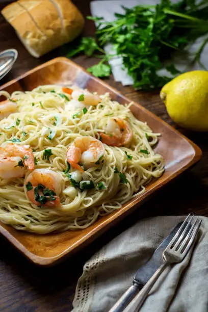 Shrimp scampi with angel hair pasta surrounded by cooking ingredients