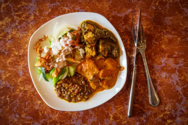 Authentic Indian cuisine buffet plate with tikka masala birista fried onions rajma beans and Saag paneer spinach and cheese