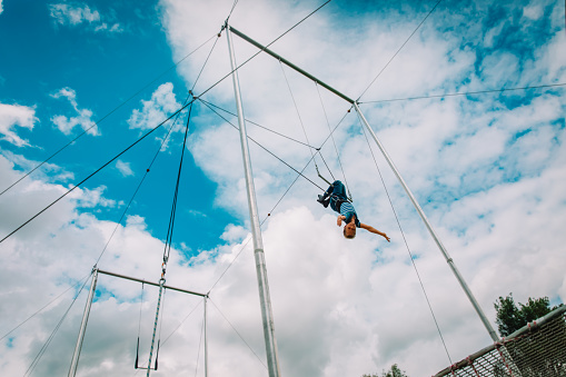 kid having swing on a high flying trapeze, boy learning acrobatics, vacation activities for kids