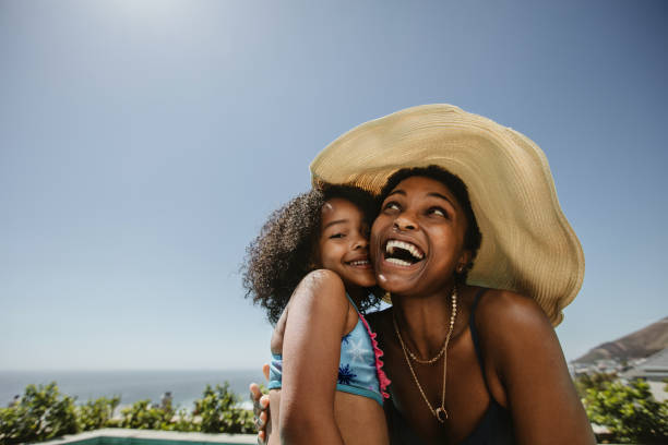 Woman with her daughter having fun at the poolside Woman wearing hat enjoying summer vacation with her daughter. African woman with her daughter having fun at the poolside. south africa youth day stock pictures, royalty-free photos & images