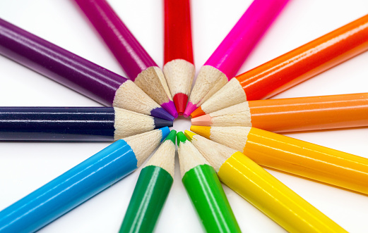 Set of crayons with different colors on a bright green background. Reference to children's play, abstract backgrounds and textures, coexistence between people and motor development.