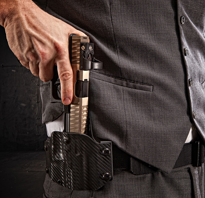 Pistol being drawn from a weapon holster on a man's belt.