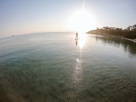 Senior man ridding paddle board on a beautiful sunrise