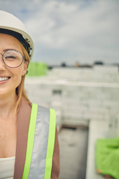 istock Pleased female builder in eyeglasses standing outdoors 1265683568