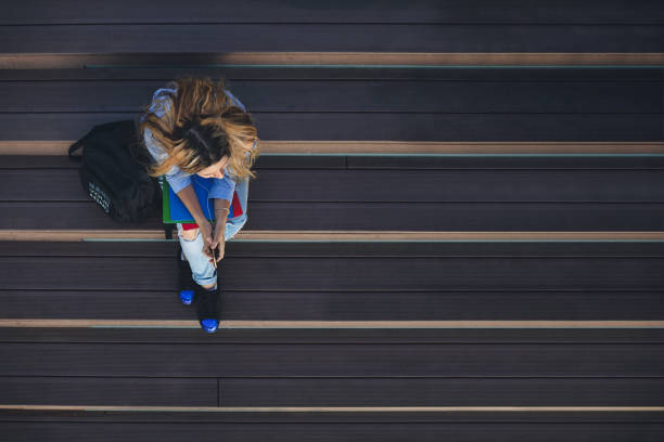 istock Student girl on campus sitting on stairs and using a smartphone while waiting for classes to begin. Back to school concept 1265687832