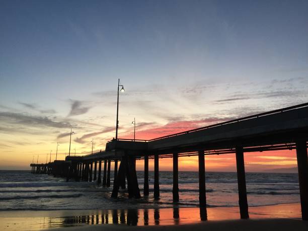 istock Landscape view of pier over sandy beach shore at sunset 1265697024