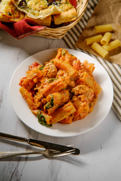 Creamy Italian Sausage Rigatoni Creamy Italian tomato sauce rigatoni with spicy sausage and side of cheesy olive garlic bread vodka sauce stock pictures, royalty-free photos & images