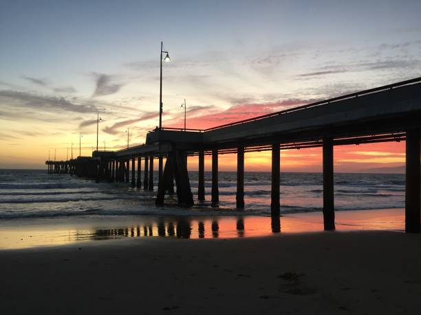 istock Landscape view of pier over sandy beach shore at sunset 1265698927