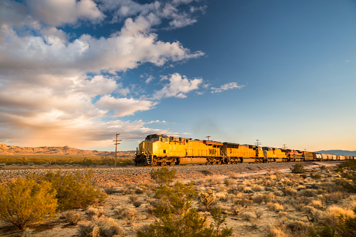 Freight train hauling goods travels on the tracks in the dry California desert