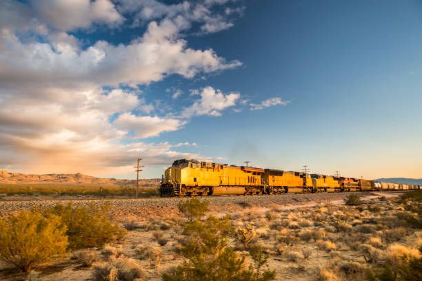 Cargo train rolls through the desert Freight train hauling goods travels on the tracks in the dry California desert freight train stock pictures, royalty-free photos & images