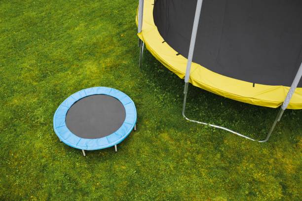 istock small trampoline near big one with round mat, size comparison, green lawn background 1265711058