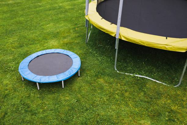 istock small trampoline near big one with round mat, size comparison, green lawn background 1265711101