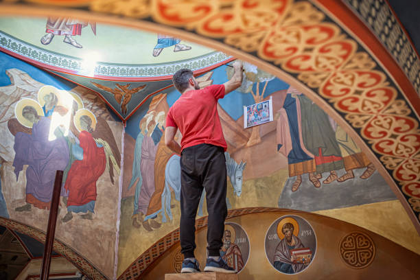 joven artista pintando las paredes de una iglesia ortodoxa con un pincel - restoring art painting artist fotografías e imágenes de stock