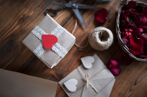 Close up of handmade wrapped gift with plastic free materials, Red Heart on the top, Valentine`s Day concept.